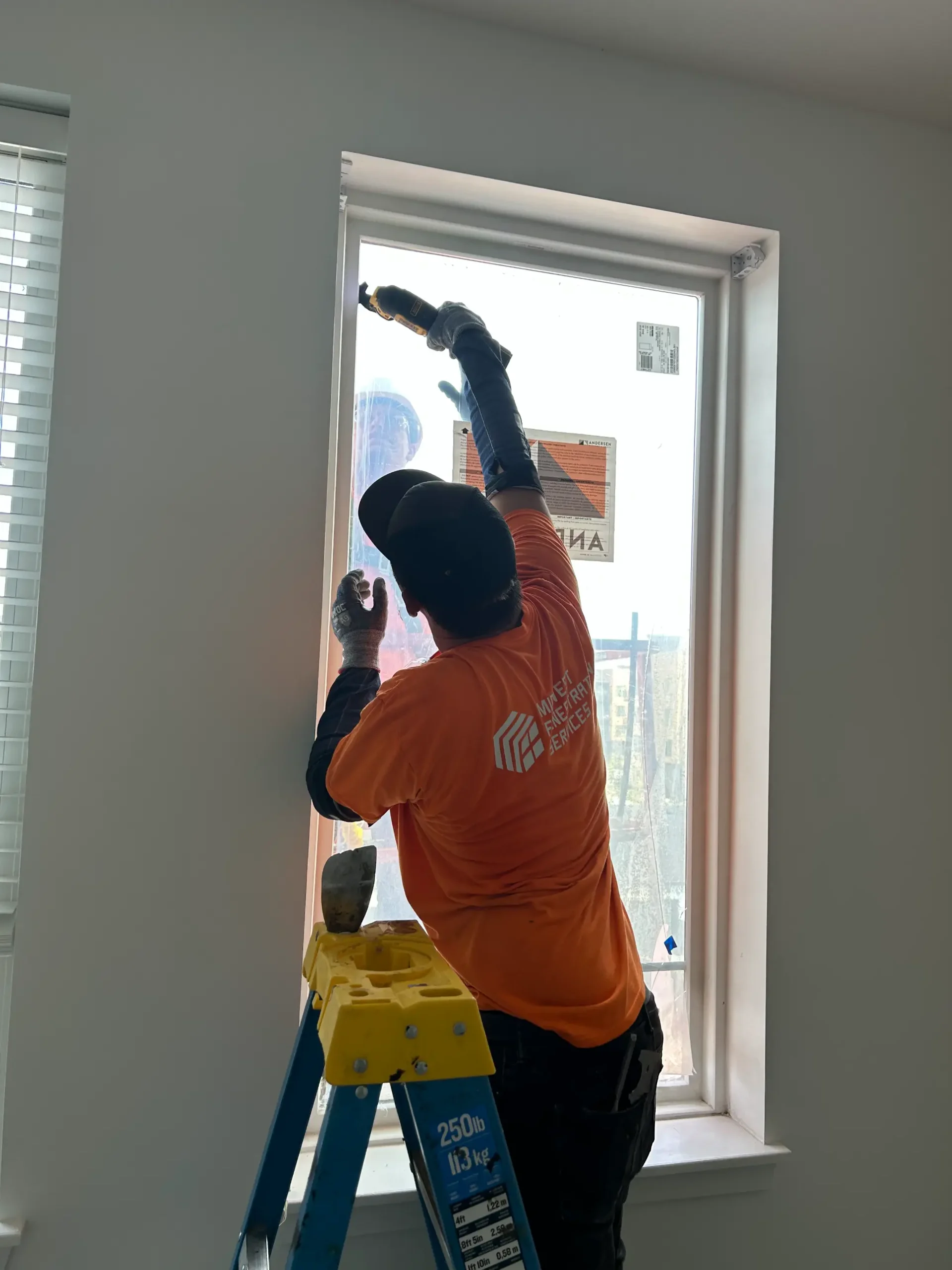 Worker applying insulation film to residential window